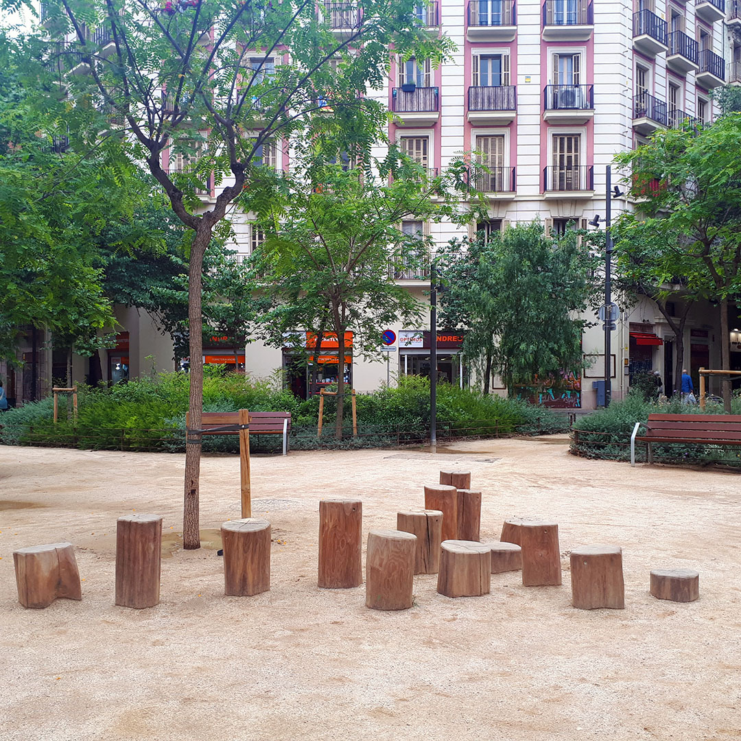 Tree stumps used as a play area for children amidst Barcelona's Superblocks.