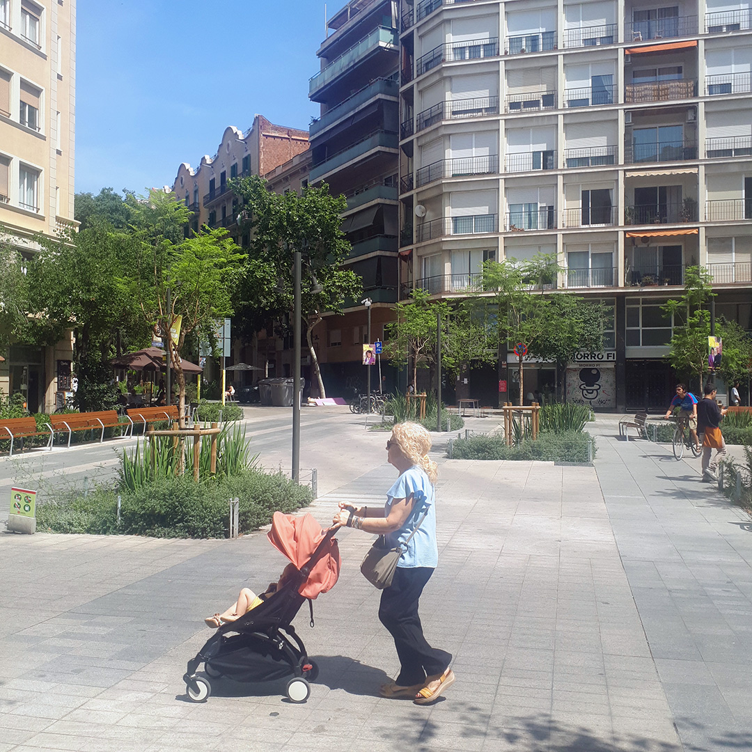 A person pushes a baby stroller through a square amidst Barcelona's Superblock.