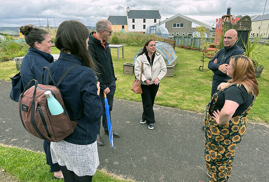 People talking during a walk tour beside a community garden in Stranraer.