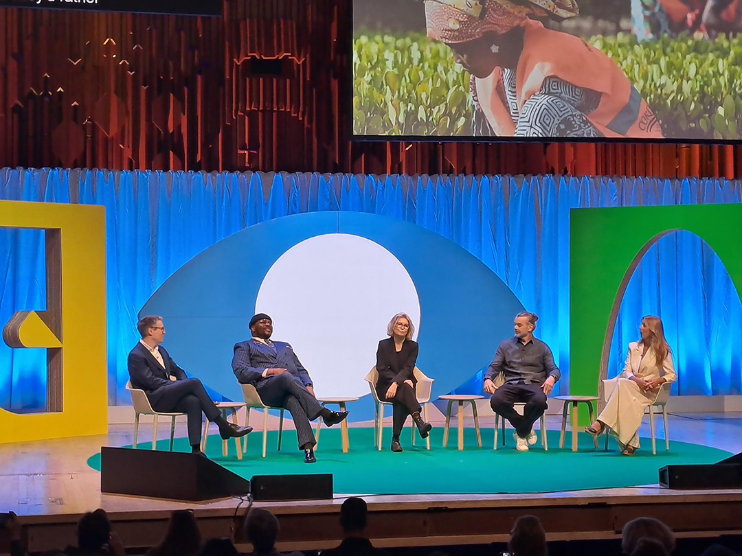 A group of people sitting on a colourful stage presenting to the world design conference